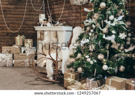 Decor of the Christmas photo zone: a Christmas tree, rocking chair, fireplace and many gifts. Cozy New Year's photo zone. Christmas concept