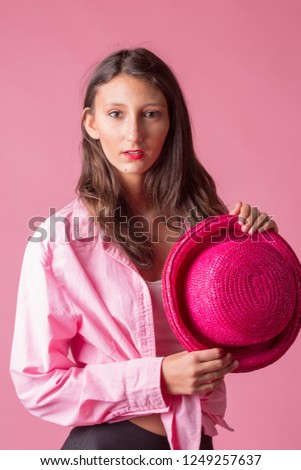 Studio shot of a teen girl in the studio dressed in pink with a hat