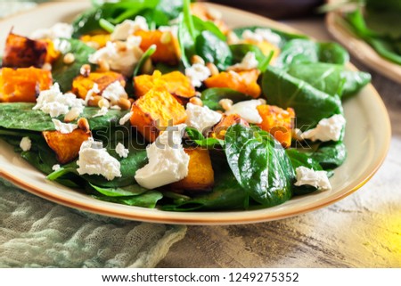 Roasted pumpkin salad with spinach, feta and pine nuts. Autumn dish