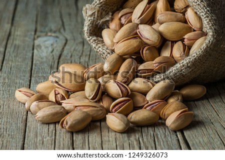 Pistachio in nutshell on black wooden rustic backdrop in burlap sack, composition of pistachios great for healthy and dietary nutrition. Concept of nuts Royalty-Free Stock Photo #1249326073