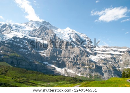 On the way to climb Jungfrau, Switzerland, take a picture of a field with snow-covered mountains and trails.