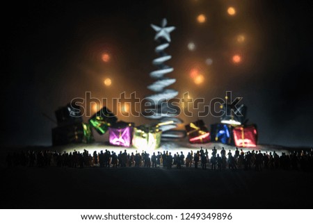 New year or Christmas holiday shopping concept. Store promotions. Silhouette of a large crowd of people watching at a big fir tree and gift boxes. People on snow ready to shopping. Selective focus