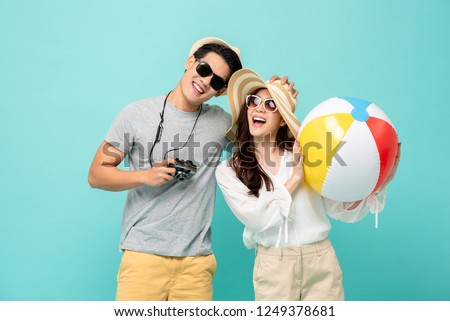 Lovely Asian couple in summer casual clothes and beach accessories studio shot isolated on light blue background