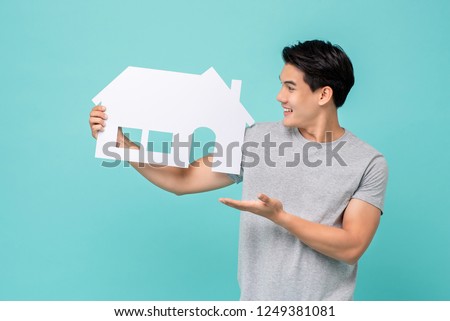 Portrait of young handsome Asian man holding paper home for real estate concept