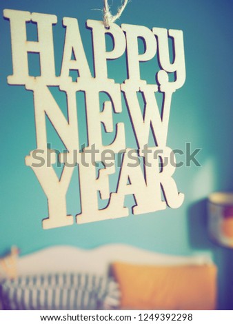 Wooden letters HAPPY NEW YEAR on blurred background of blue painted bedroom wall with white bed and yellow pillow. New Year New You, Start the active days in 2019 theme. (selective focus)