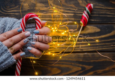 Luxury short manicure on a dark wooden background. cozy winter nails. christmas candy with lights 