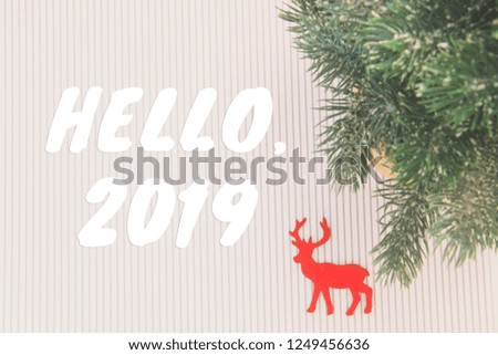 White wooden stencil of deer and branches of spruce on a light background.