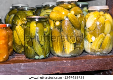 Glass jar with pickled cucumbers in basement on wooden shelf
