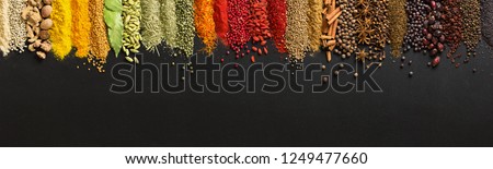 Wide variety spices and herbs on background of black table, with empty space for text or label. Royalty-Free Stock Photo #1249477660