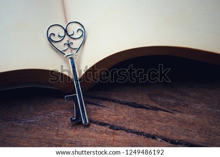 close up heart key and open book on old wood table, love story, happy valentine's day concept, vintage tone