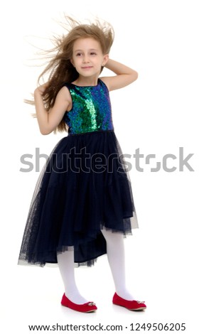 Portrait of a positive and stylish little girl in a summer dress, rejoices in the wind that blows and moves her dress and hair. The concept of beauty and fashion. Isolated on white background.