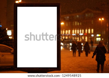 city outdoor billboard mockup winter city with snow going. Glows in the darkness of the night city.