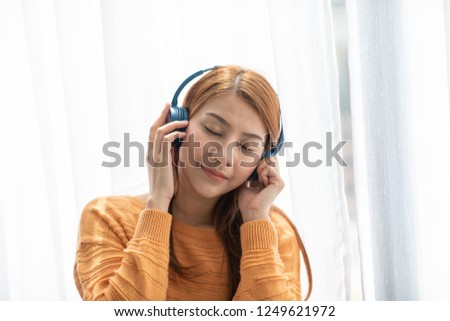 Beautiful Attractive Asian young woman listen music and sitting on sofa in living room feeling so relax and comfortable in holidays,Selective Focus,Recreation concept