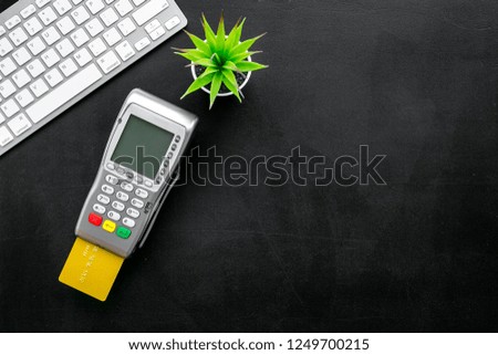 Electronic payments, online payments concept. Bank card inserted to payment terminal near computer keyboard on black background top view space for text
