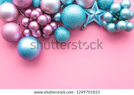 Christmas and New Year symbols. Toys for festive tree. Blue and pink balls and stars on pink background top view copy space border