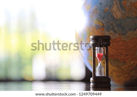 Back light of a small brown hourglass. The globe is the background selective focus and shallow depth of field