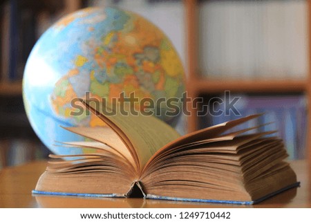 Close-up of old book opened on library table The globe is the background selective focus and shallow depth of field