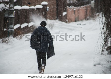 lonely man walking on a winter snow-covered street during a snowstorm, cold weather, walk in the fresh air, put a hood on his head from the wind, a pedestrian walking on snowdrifts