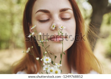 Woman sniffs wildflowers in nature                      