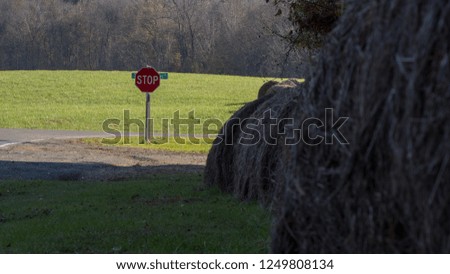 Stop sign on country road with rows of hay on the side of the road
