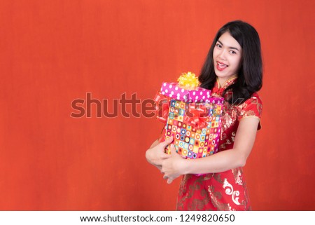 beautiful girl in the Cheongsam red dress up holding gift box on red background, The symbol of Chinese New Year
