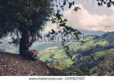 Young male photographer taking pictures of beautiful valley in Malaysia Cameron Highlands 