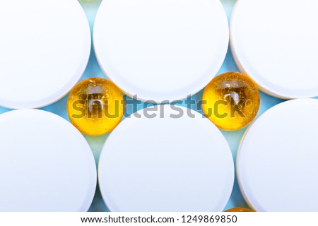 Background of white and yellow drugs close-up.Top view of fish oil for good health on a white background from pills. Extra food.