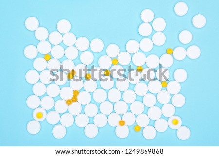 Top view of fish oil for good health on a white background from pills. Omega-3 fat capsules are yellow on a blue background and white pills. Red heart pills in the background.