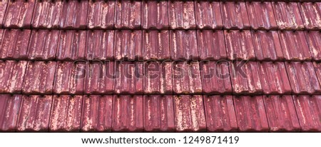 weathered and old red colored classic stone roof tiling with faded out colors, architecture pattern background