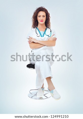 Young medical doctor woman sitting. Full length portrait isolated