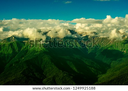 Exciting view over green hills of caucasus mountains and high clouds under clear blue sky