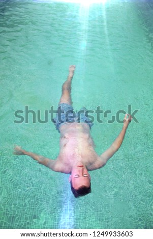 beautiful modern photo of young caucasian attractive male model relaxing and sunbathing in green pool outside in sunny summer hot day on vacation alone enjoining life 