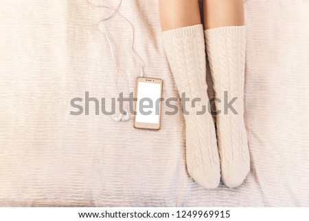 Closeup of female legs in pink socks next to a cell phone and headphones
mocup