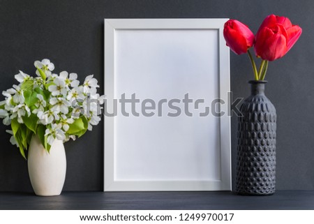 Mockup with a white frame and red tulips in a vase on a dark background