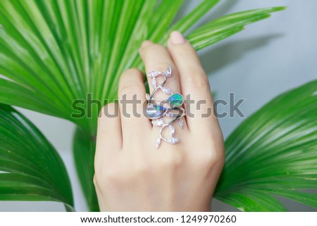 Woman's hand wearing an opal gemstone ring, silver ring close up
