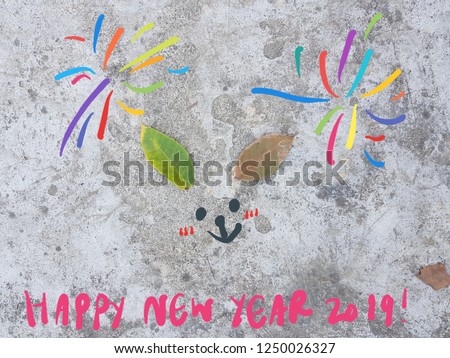 Happy New Year 2019 card with cute little bunny ears made of fallen leaves on grunge floor-fireworks and face drawing  