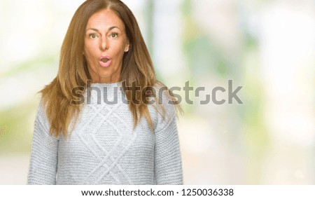 Beautiful middle age adult woman wearing winter sweater over isolated background afraid and shocked with surprise expression, fear and excited face.