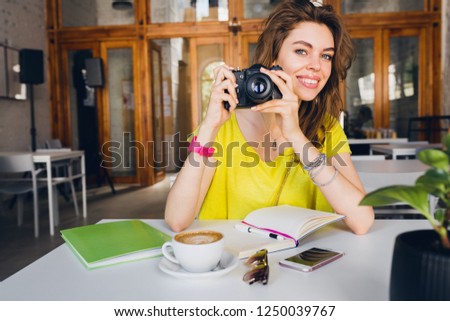 portrait of young pretty woman sitting at table, holding vintage photo camera, photographer, student learning, education, smiling