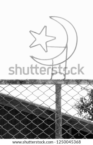 Islamic sign (crescent and star) on the chain-link fencing. 