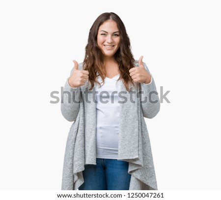 Beautiful plus size young woman wearing winter jacket over isolated background success sign doing positive gesture with hand, thumbs up smiling and happy. Looking at the camera