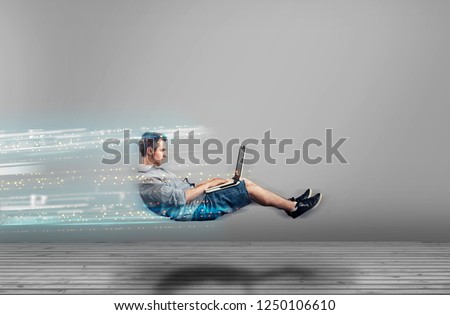 Fast levitating man in a white room using a laptop. High speed browsing. Royalty-Free Stock Photo #1250106610