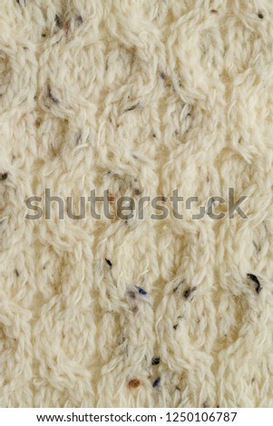 Knitted white fabric texture from wool with a relief pattern. Warm winter clothes or blanket. Handmade texture. Background of knitted sweaters decoration