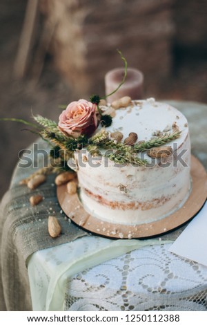 Rustic wedding cake decorated with decorated with flower, spikes of wheat and peanuts. white wedding cake