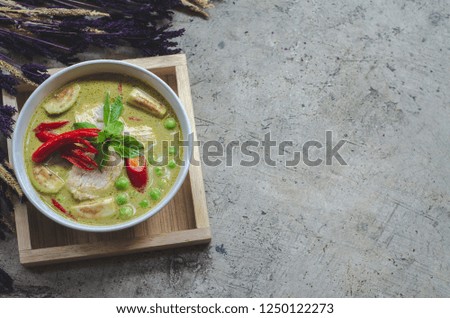Chicken Green Curry.Purple grass flowers are on the floor.Red chili in a bowl of food.