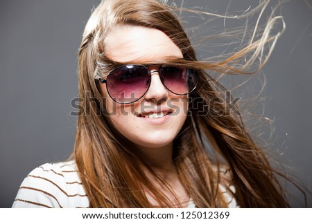 Pretty brunette teenage girl with sunglasses. Studio shot.