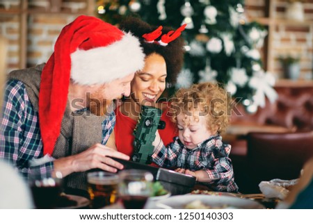 Man and mixed race woman giving toddler  Christmas gift while sitting at table. Christmas holidays concept.