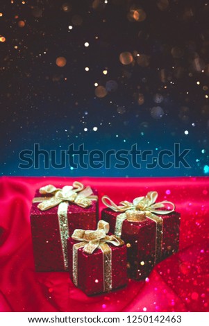 Sparkly red present boxes with Christmas lights on a red and blue background with bokeh