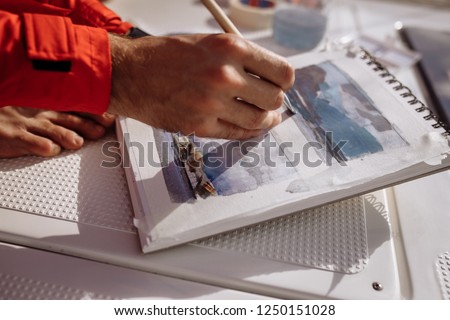 Man is drawing the landscape on boat. Man is drawing sea and mountains. Painter at work. Inspiration 