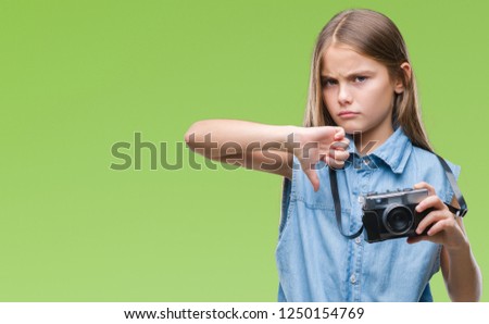 Young beautiful girl taking photos using vintage camera over isolated background with angry face, negative sign showing dislike with thumbs down, rejection concept
