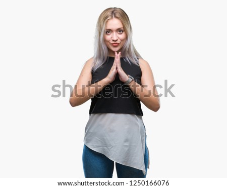 Young blonde woman over isolated background praying with hands together asking for forgiveness smiling confident.
